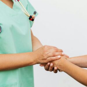 Medical weight loss provider in green scrubs gently holding a new patient's hand during a consultation