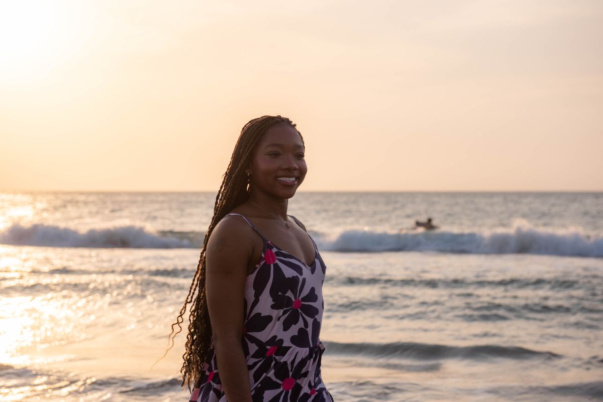 Smiling woman on the beach at sunset feeling confident after losing weight before vacation