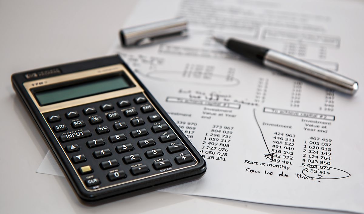 Calculator and financial paperwork on a desk — the cost and coverage of HRT
