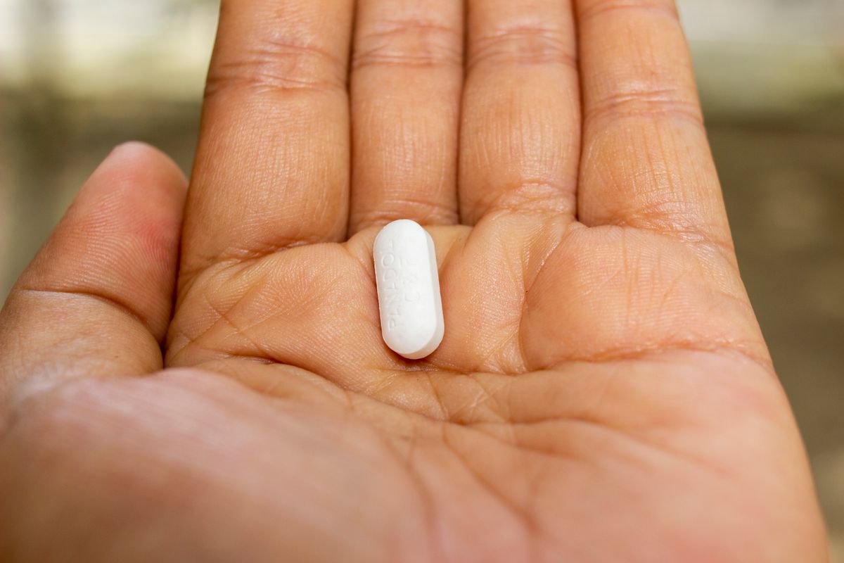 A single tablet resting in an open palm — estrogen pill option