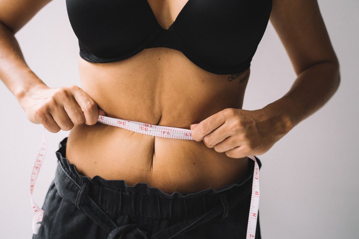 Woman measuring her waist with a tape measure — hormonal belly fat