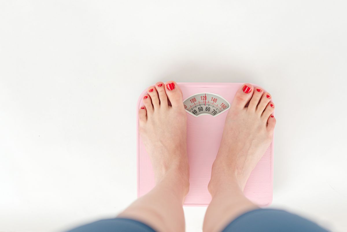 Woman standing on a bathroom scale — menopause weight gain