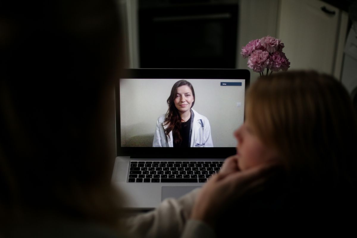 Patient on a telehealth video call with a doctor on a laptop — online HRT vs in-person