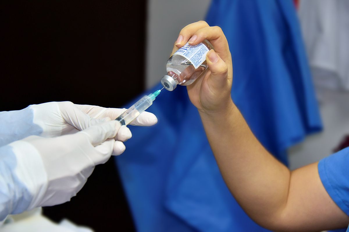 Clinician drawing medication from a vial into a syringe — testosterone injections